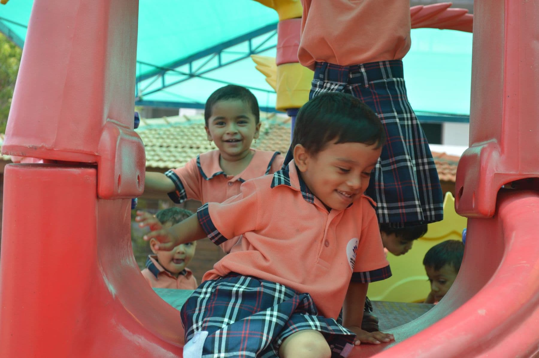 Two boys giggling inside a red play tunnel