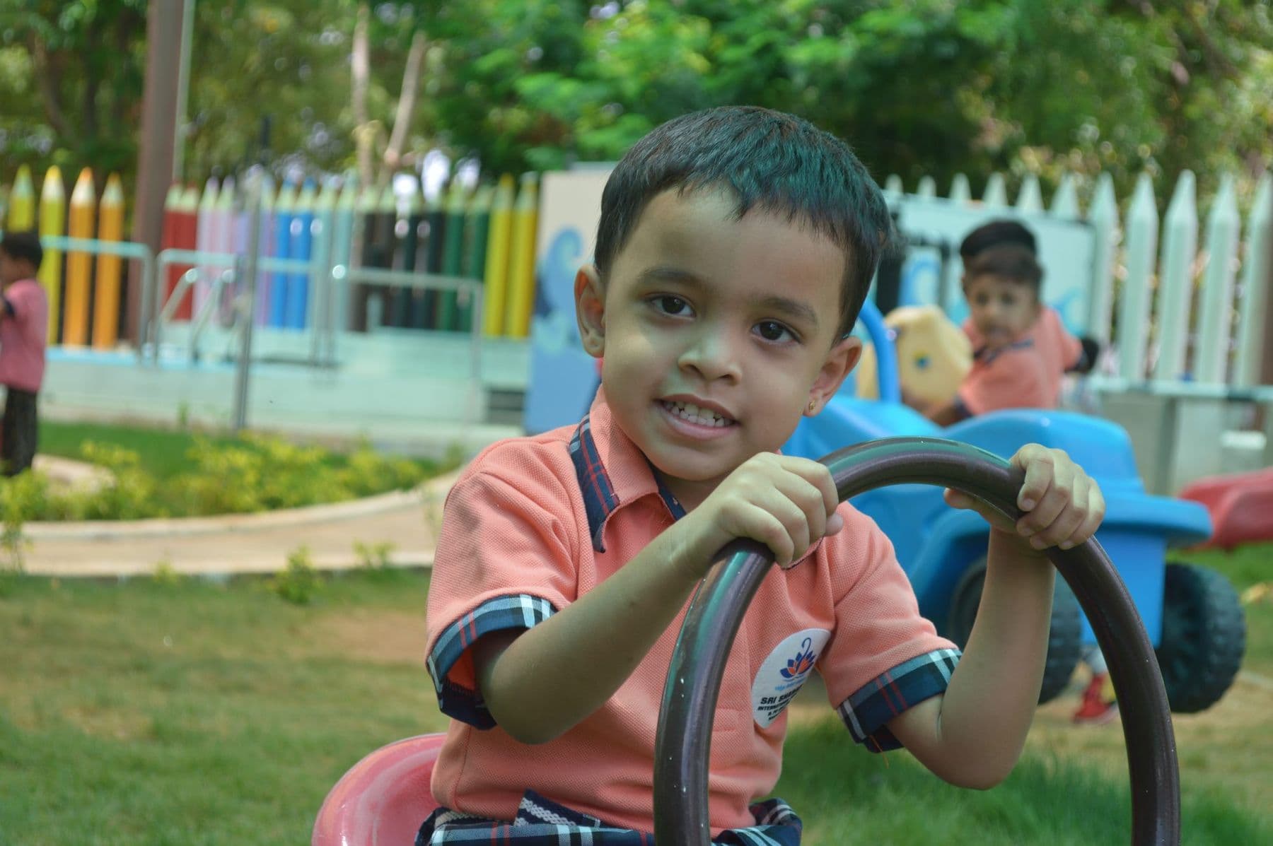 A smiling boy at the steering wheel of a ride-on toy