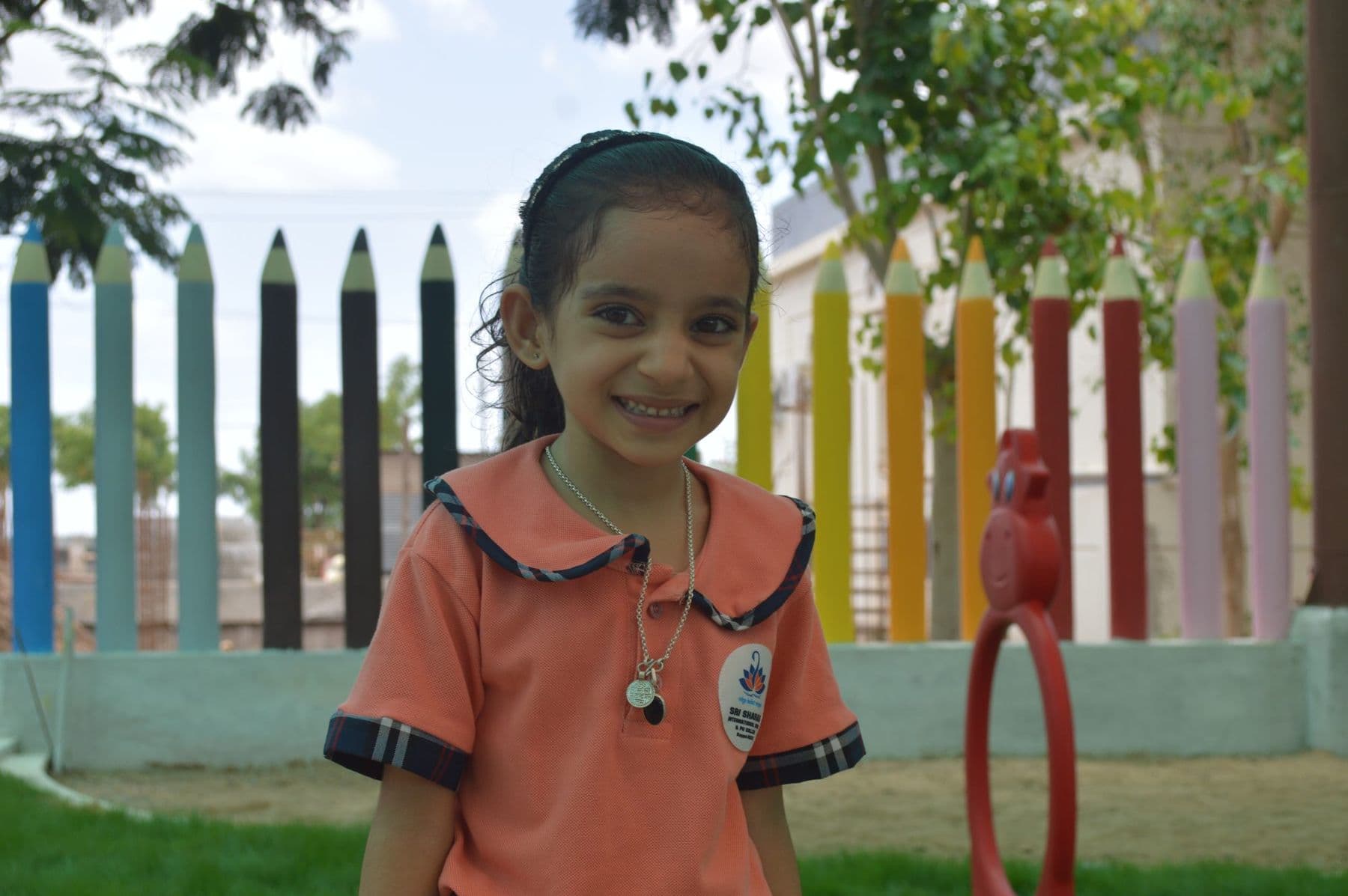 A smiling girl by the colourful pencil fence