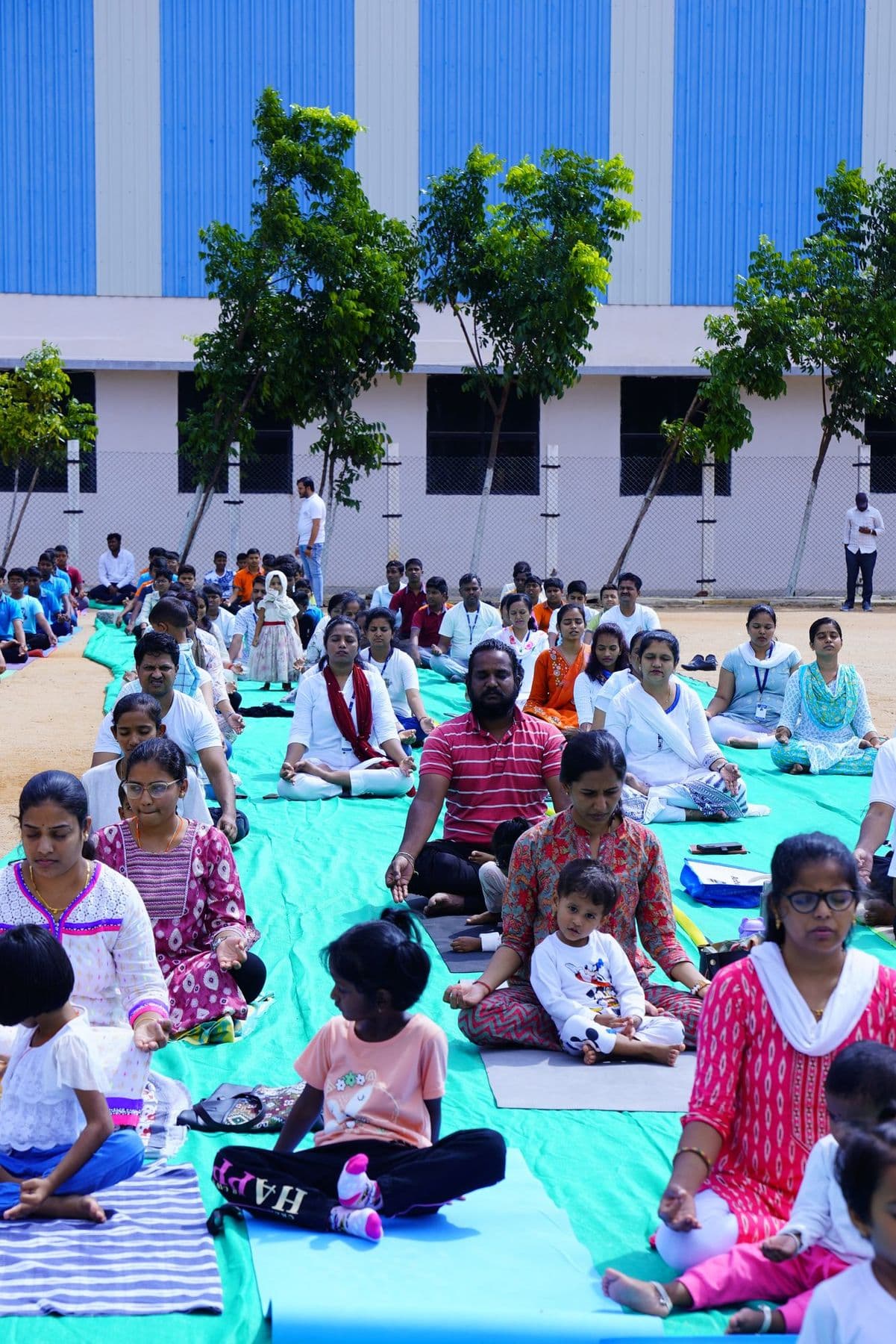 Children and parents in yoga poses at the front of the ground