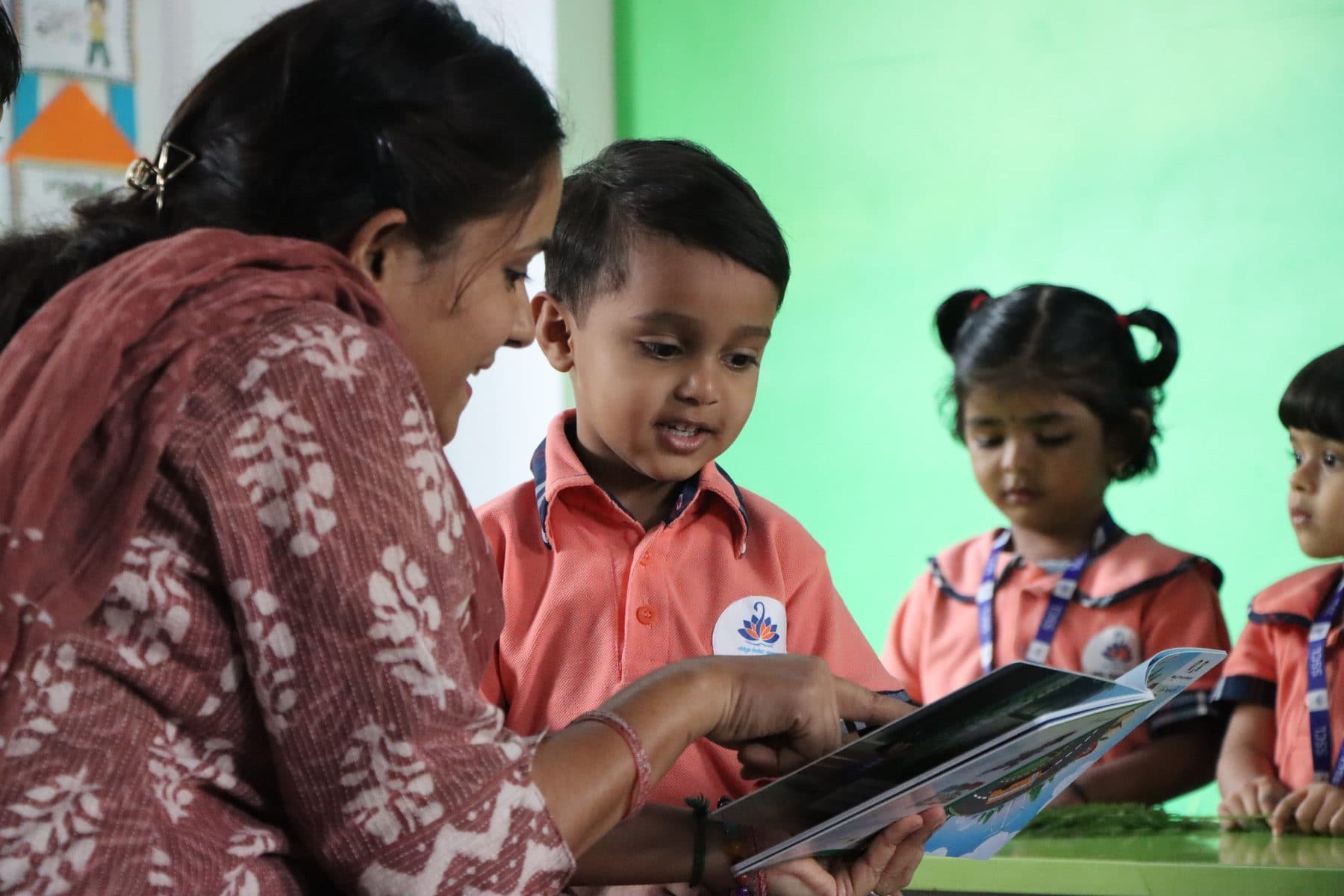 A teacher showing a picture book to a boy and girl