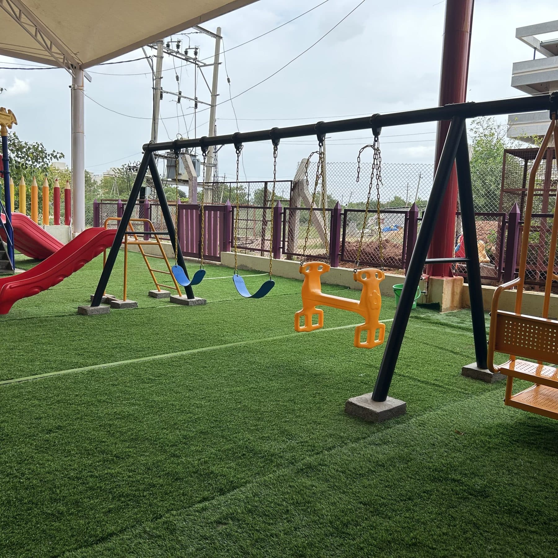 A row of swings beside the red slide