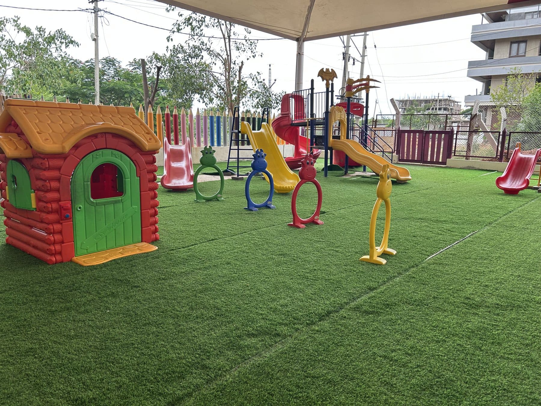 A red and green play house beside the climbing hoops