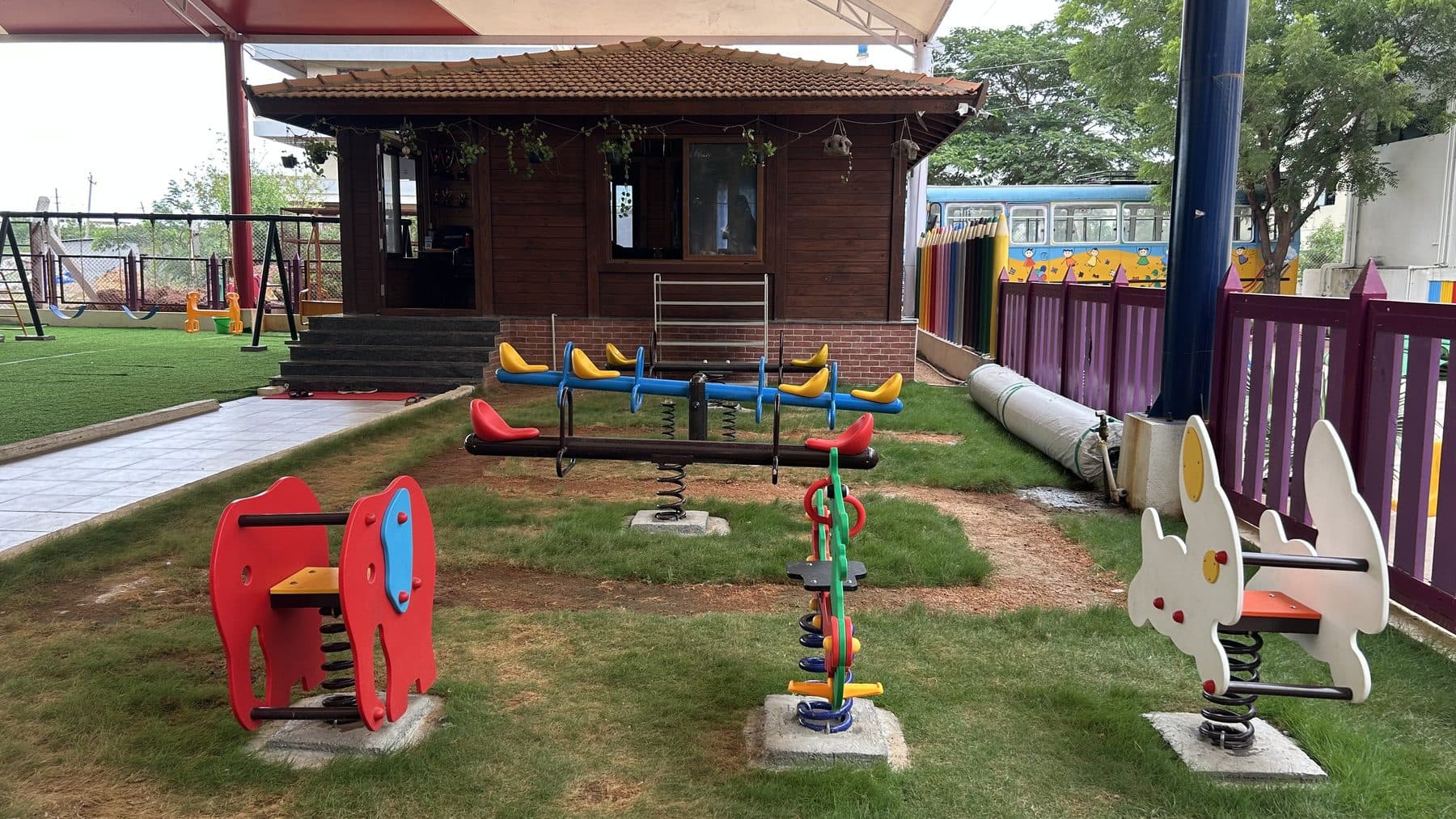 Spring riders and a seesaw in front of the wooden hut