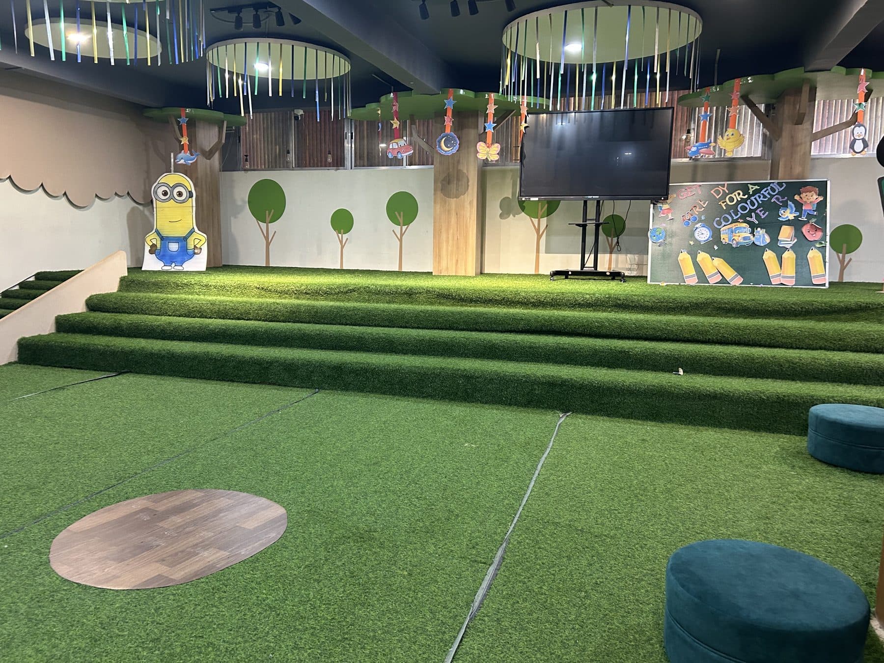 The indoor amphitheatre with grass-carpet steps and a big screen