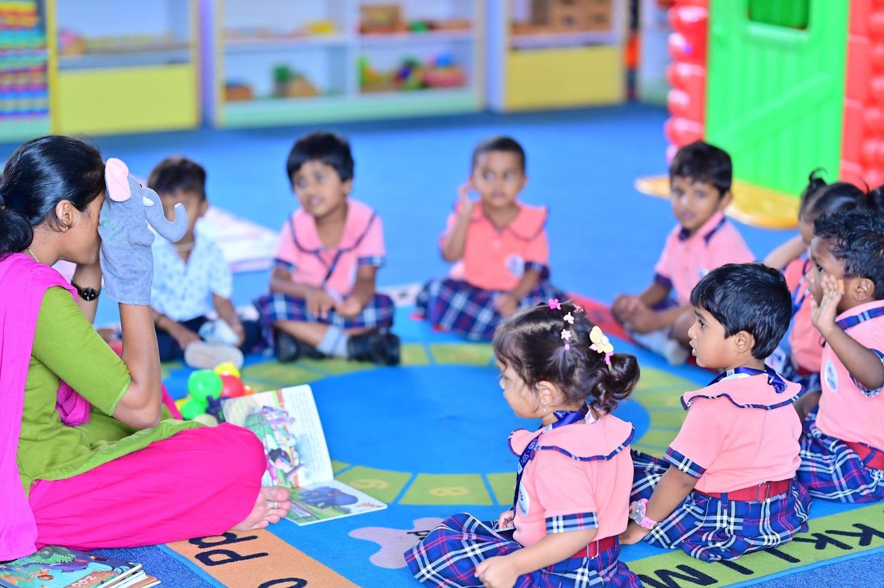 Children sitting in a circle on a colourful rug with their teacher