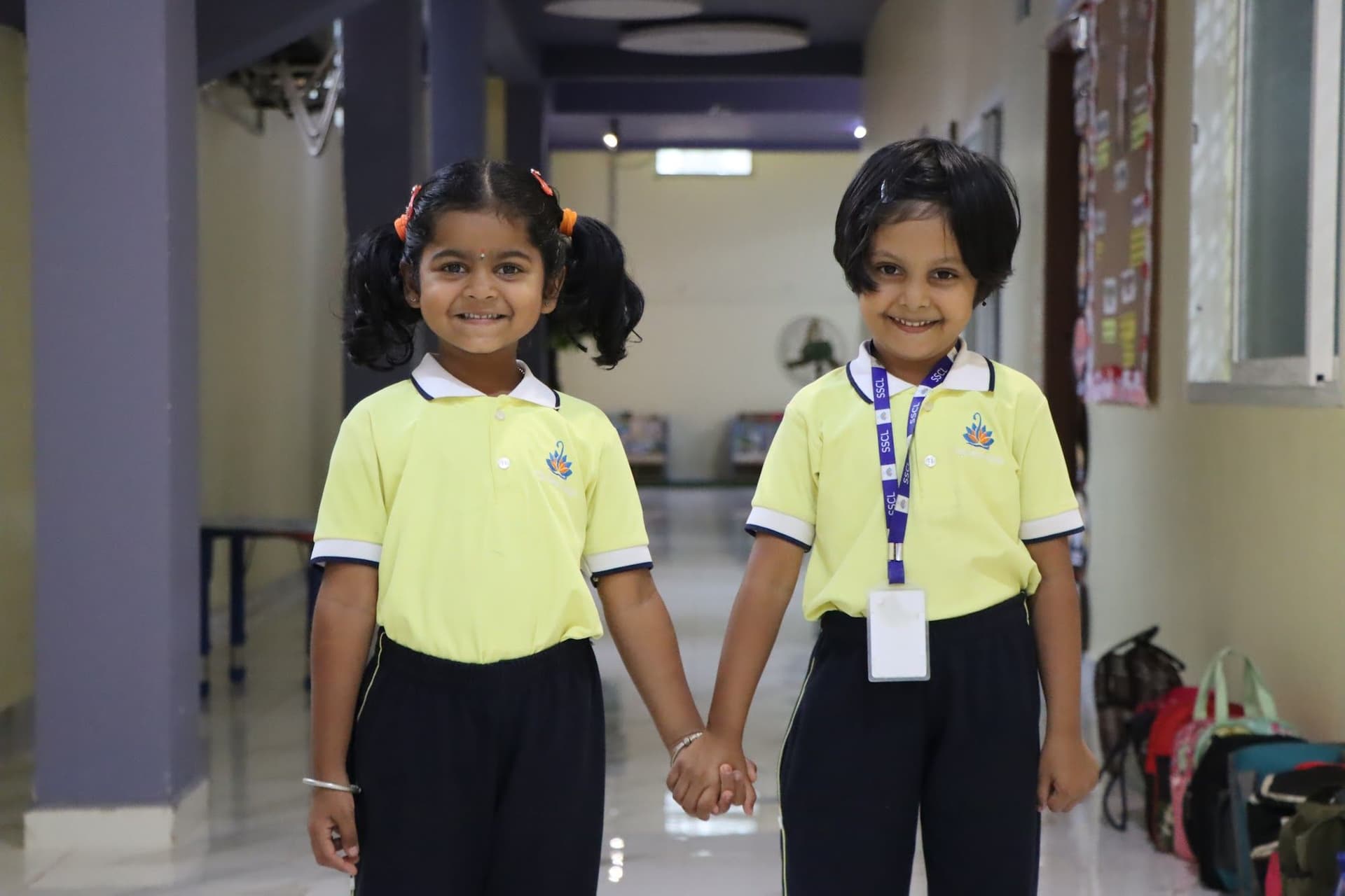 Two smiling girls holding hands in the school corridor