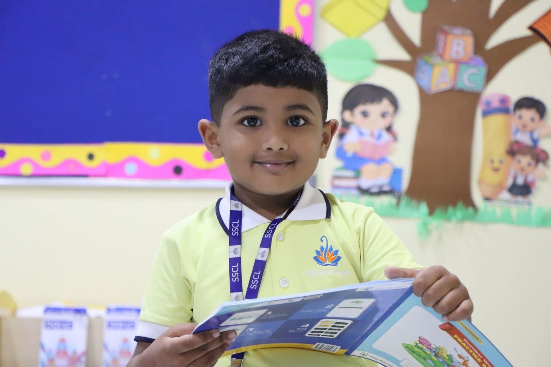 A boy proudly holding up an open picture book