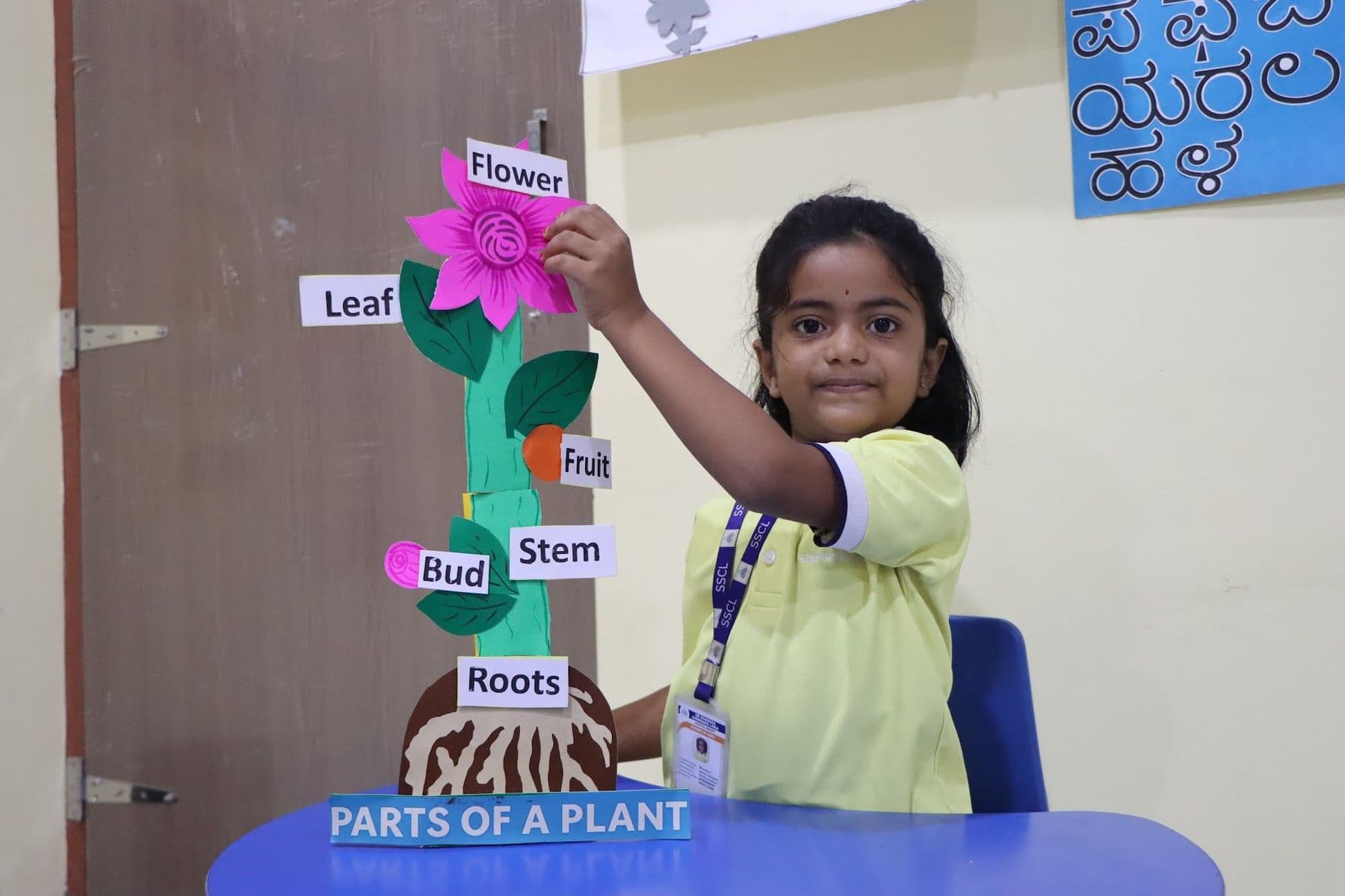 A girl pointing to the flower on a plant model