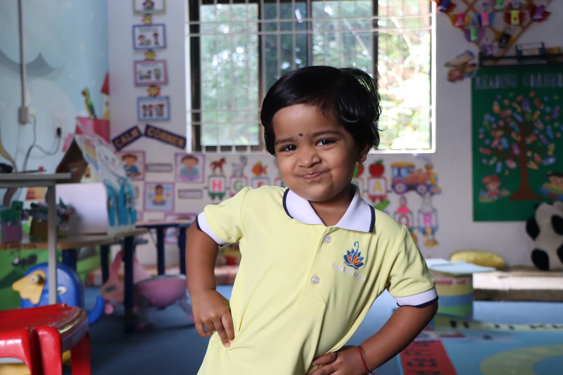 A toddler striking a happy pose in the classroom