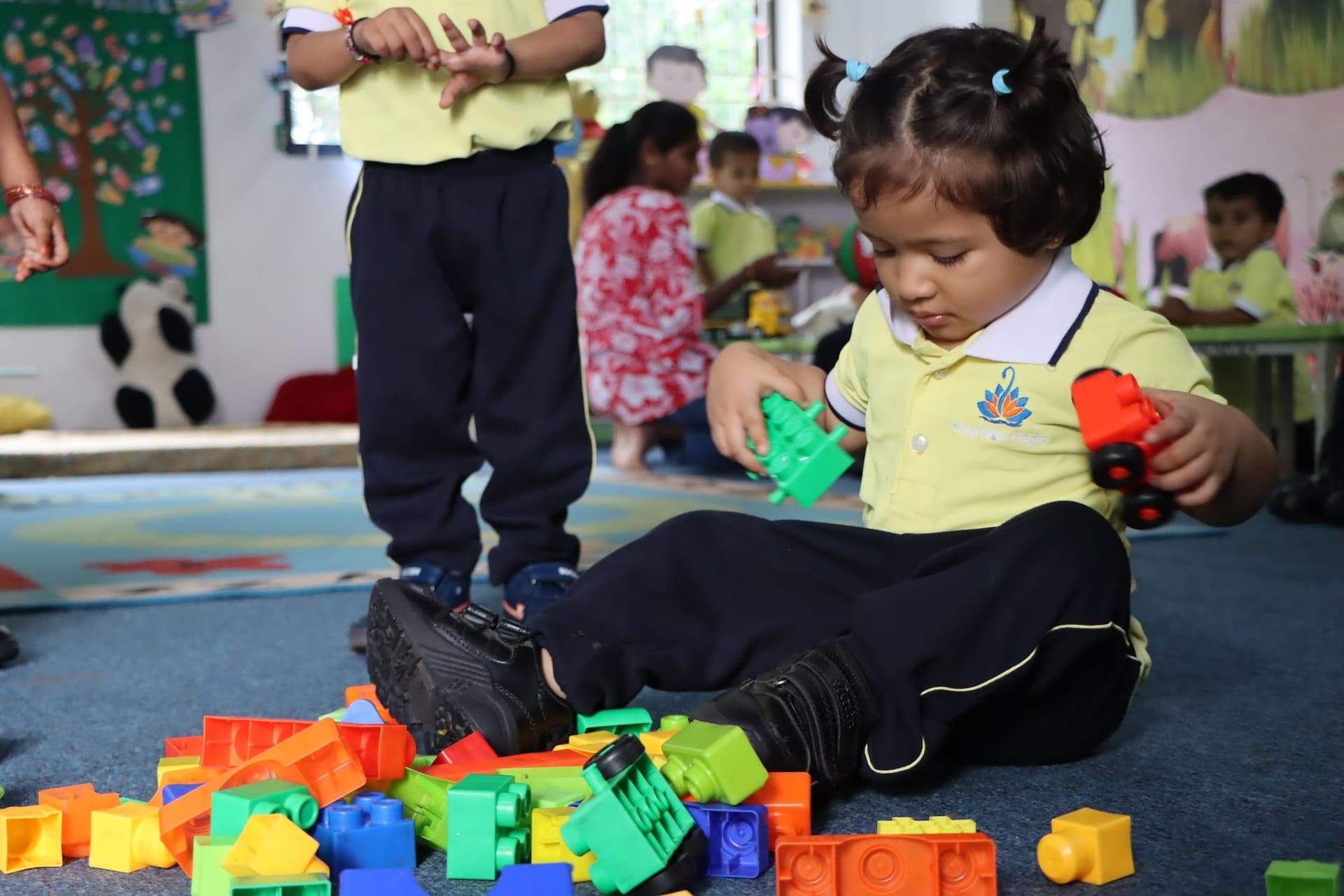 A toddler sitting on the mat playing with building blocks