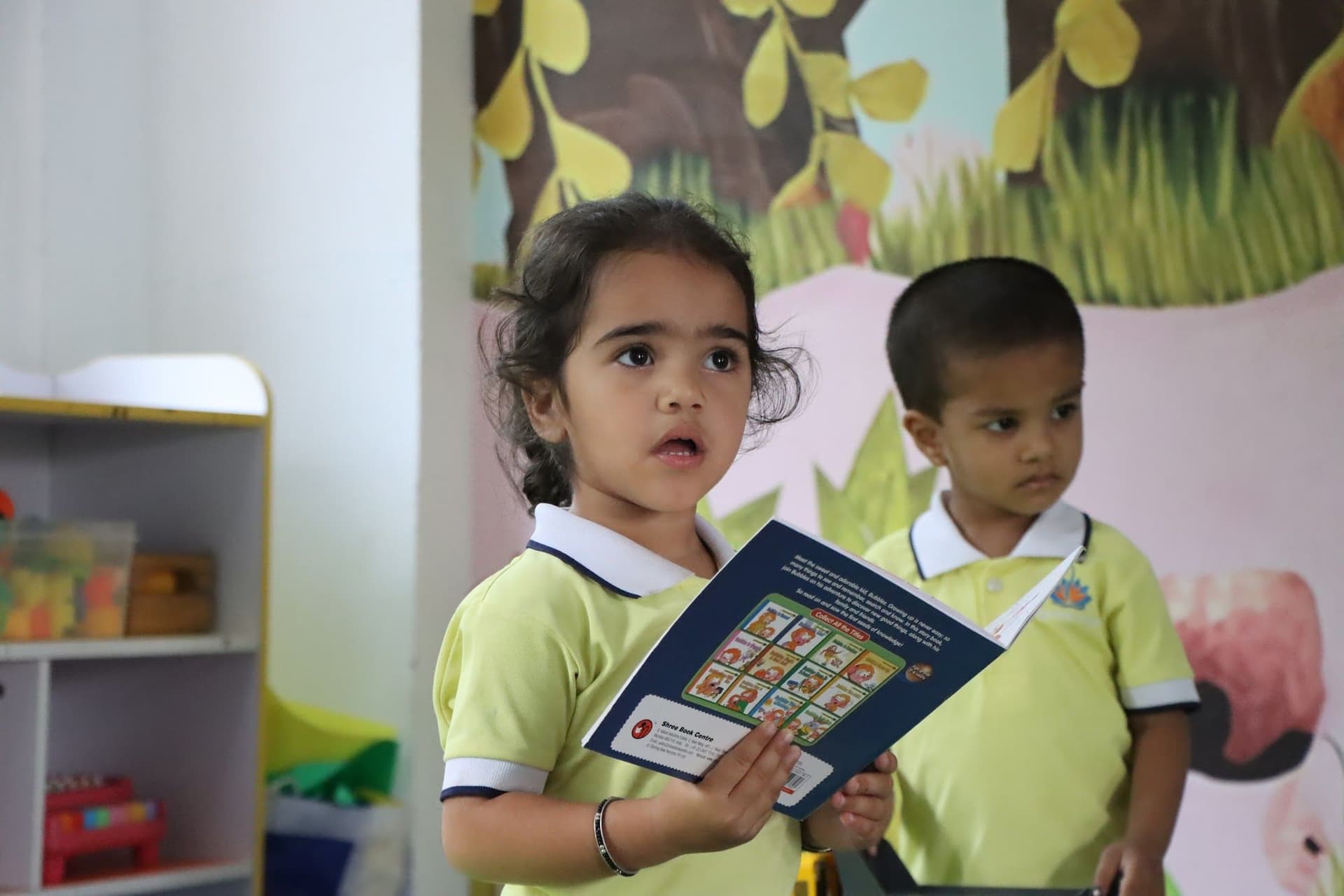 A girl reading a picture book beside her friend