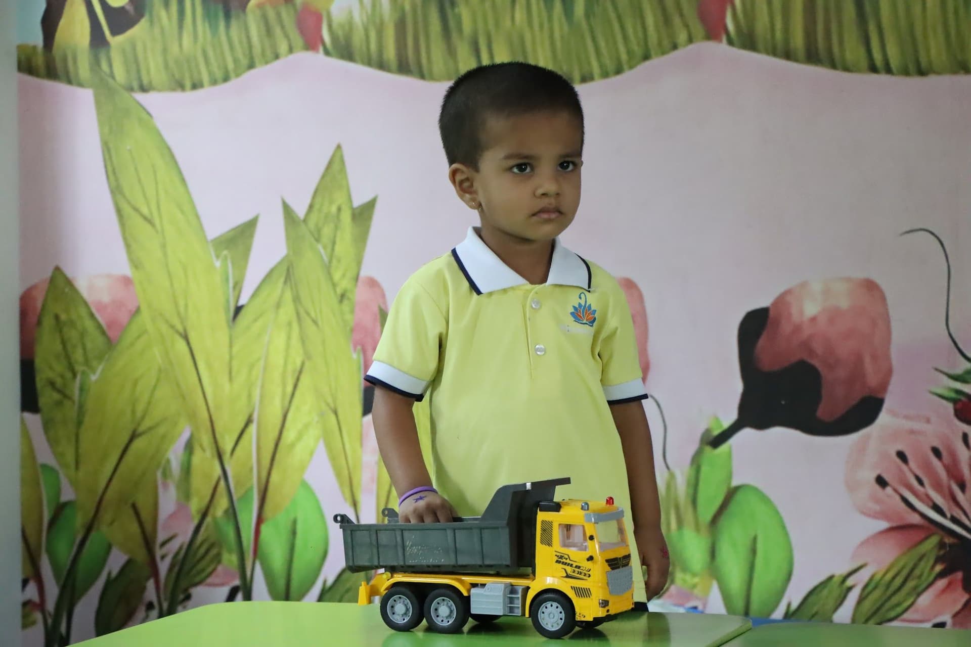 A boy playing with a toy truck in the classroom