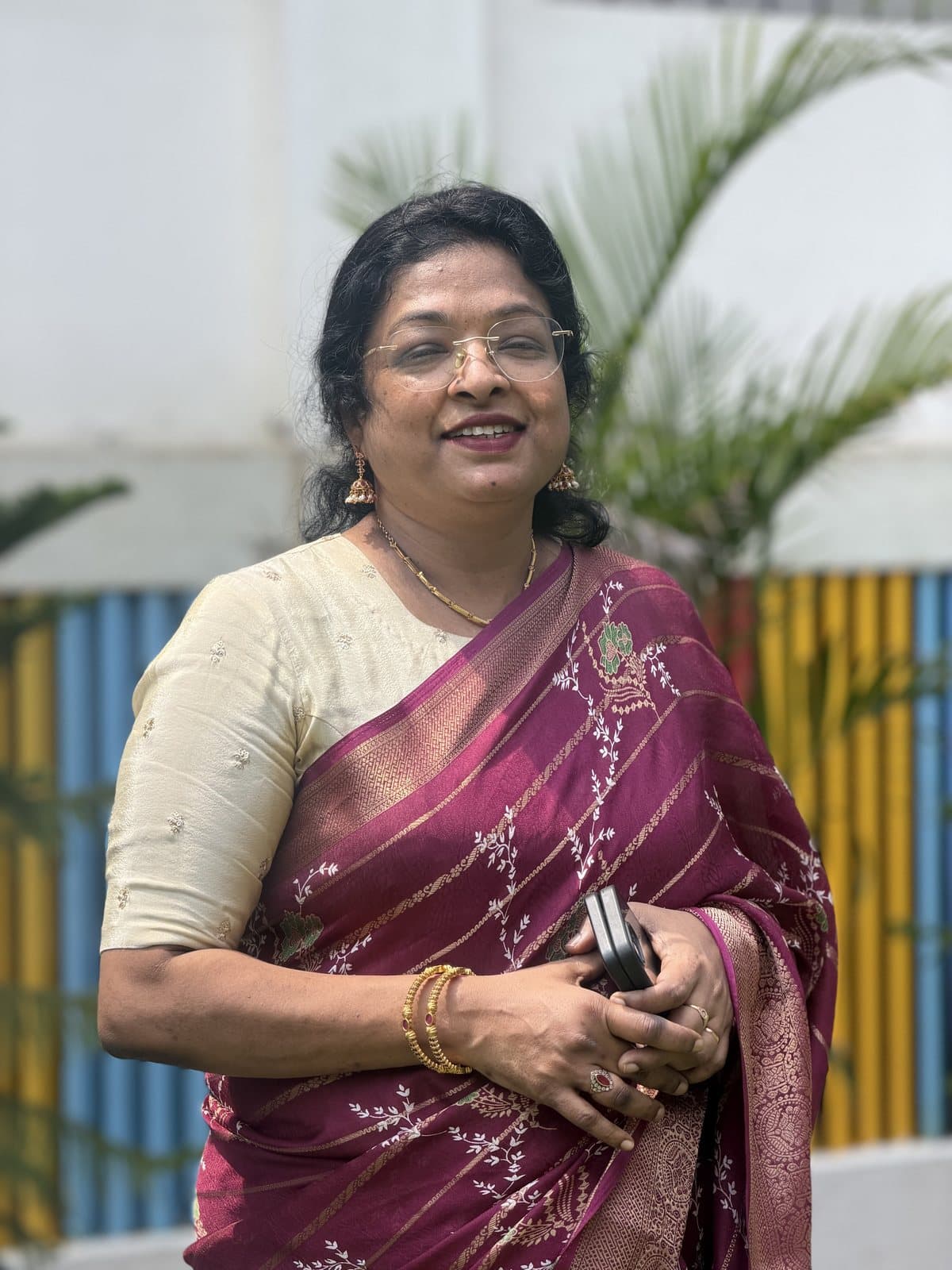 Ms. Rachel Sughandhi. Y, Principal of Sri Sharada Chinnara Loka, smiling in a maroon silk saree