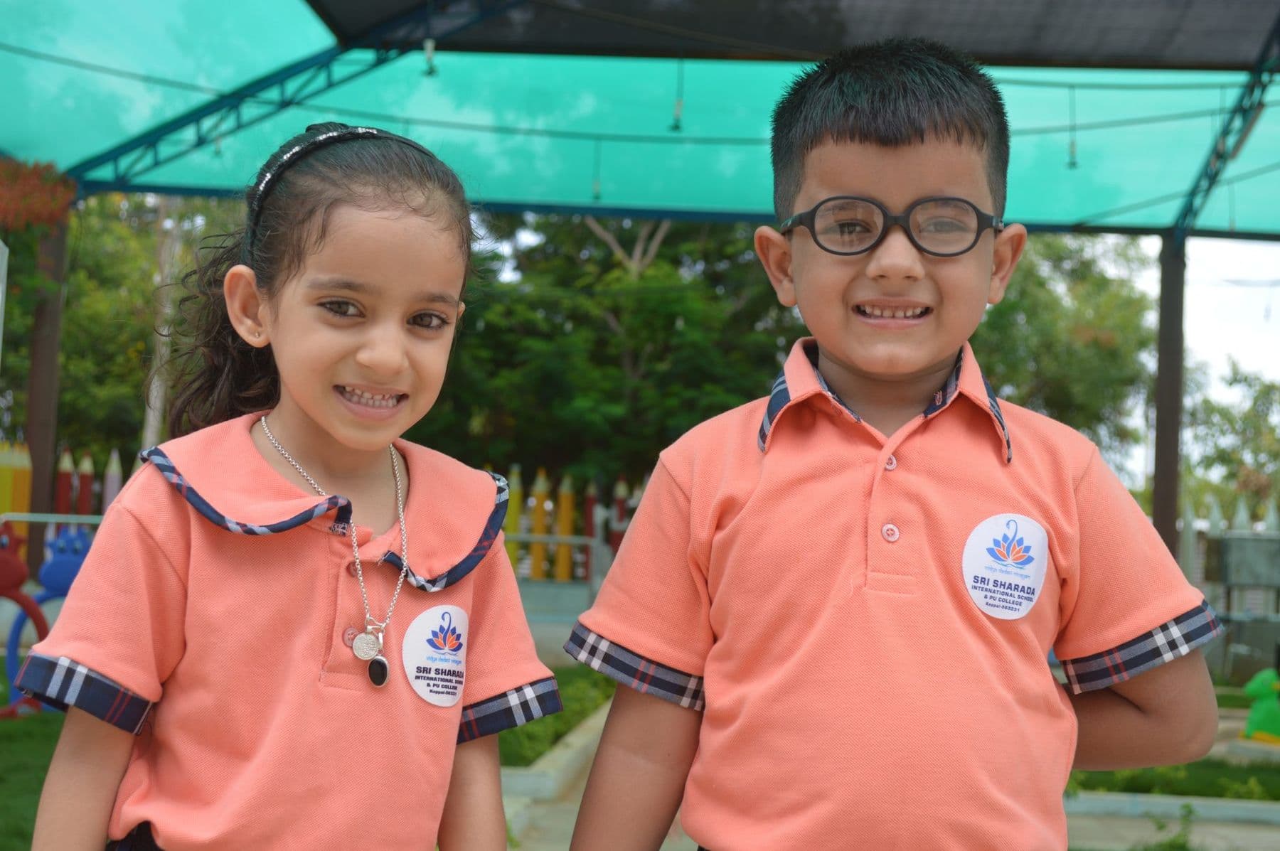 A girl and a boy in glasses grinning together