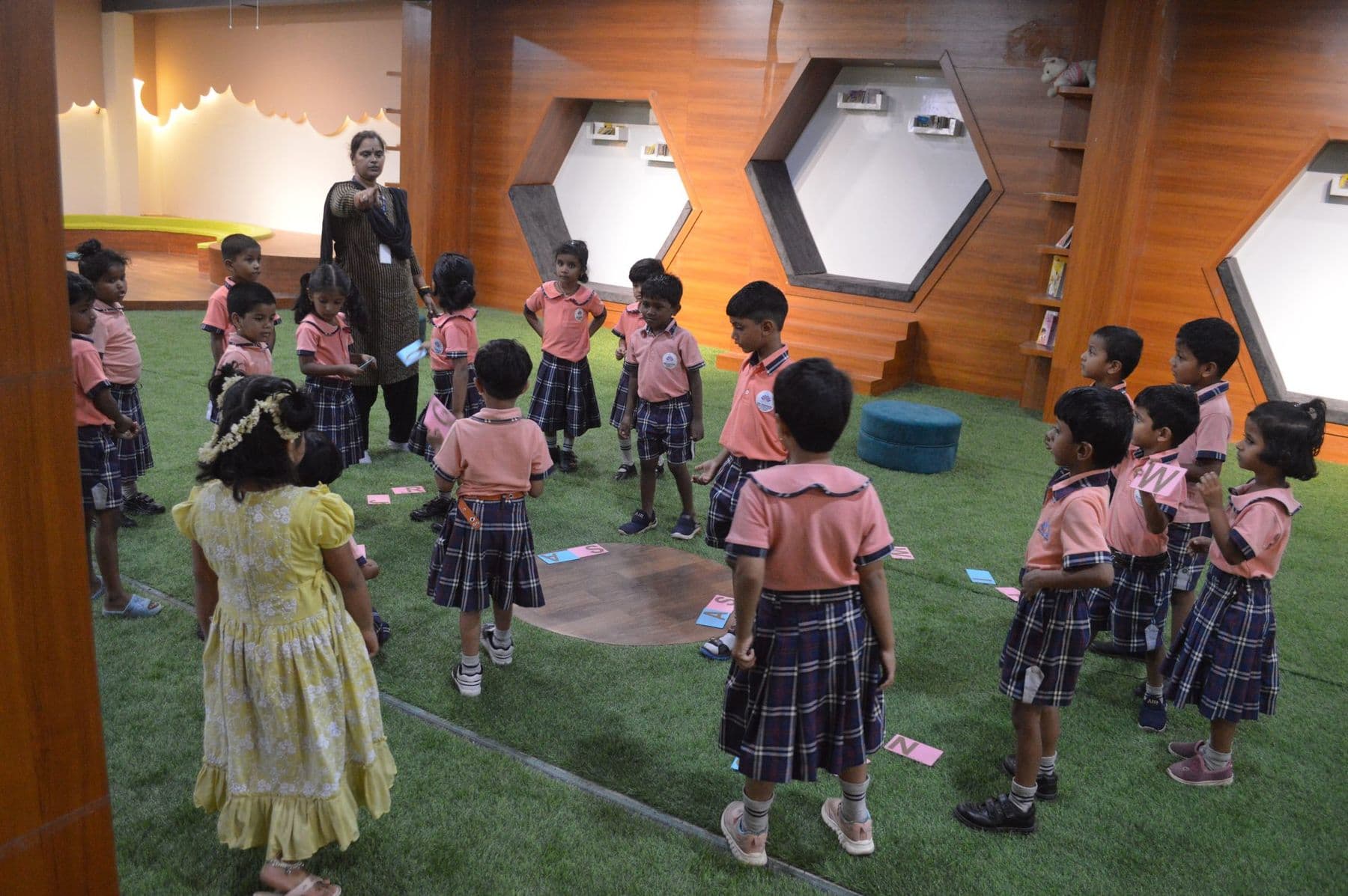 Children and their teacher playing a card game in the library hall