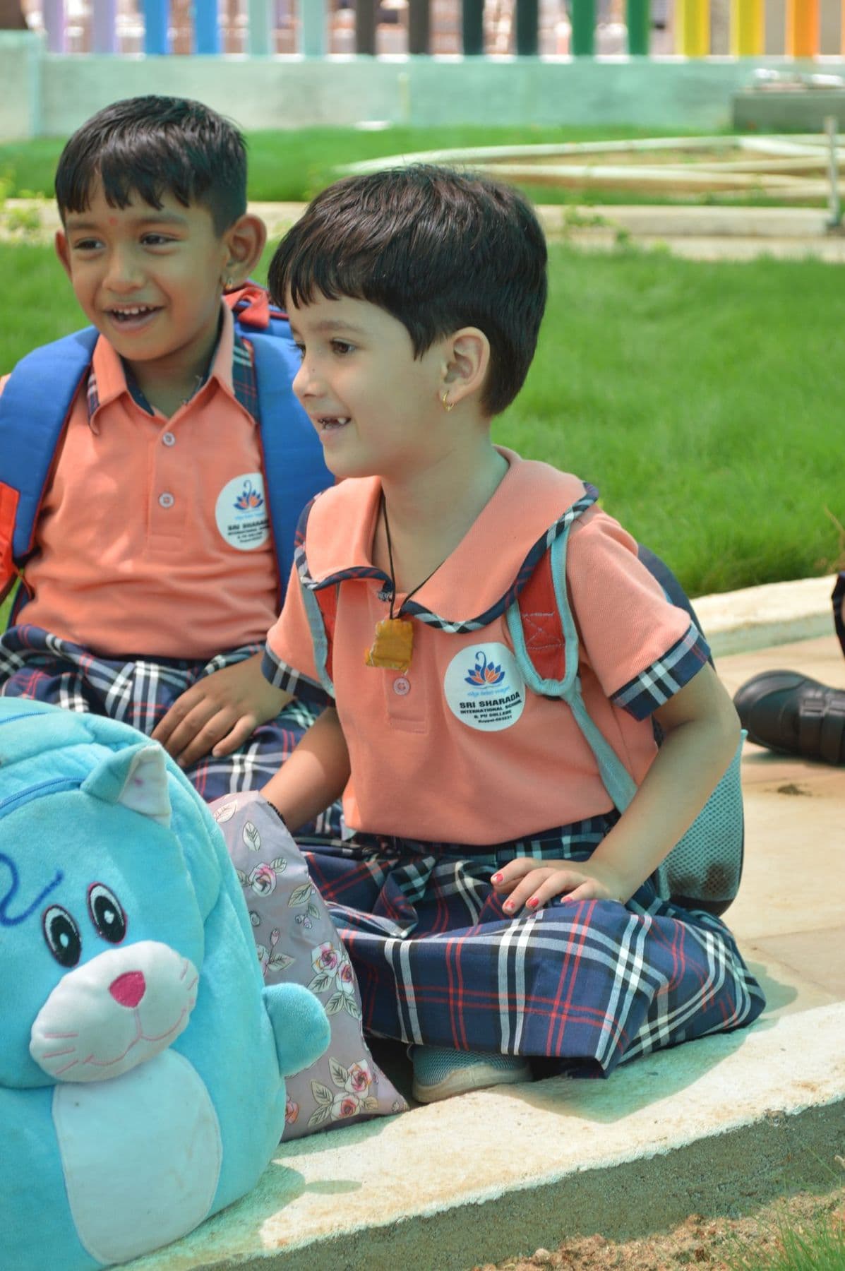 Two boys giggling beside a soft-toy backpack at home time