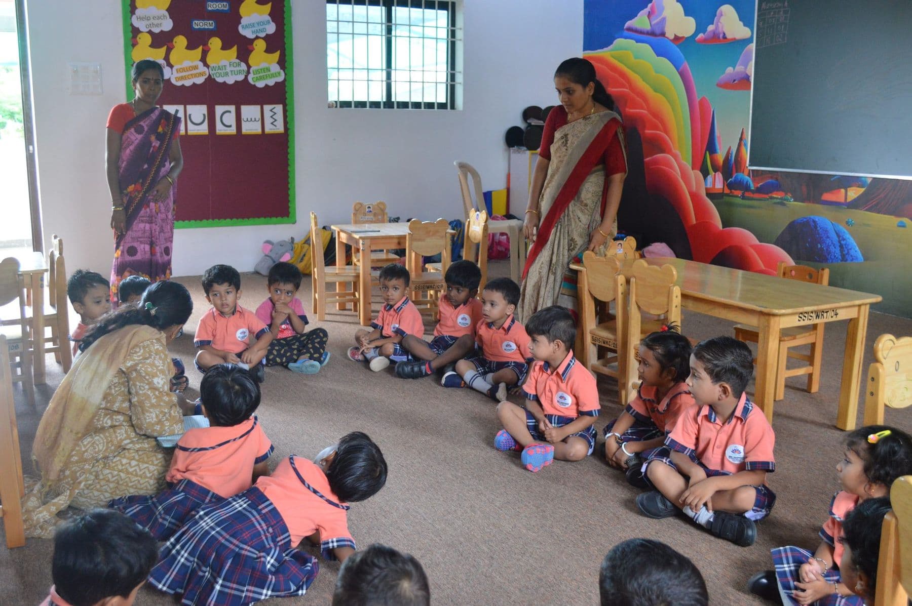 Children sitting in a circle on the classroom floor with their teachers