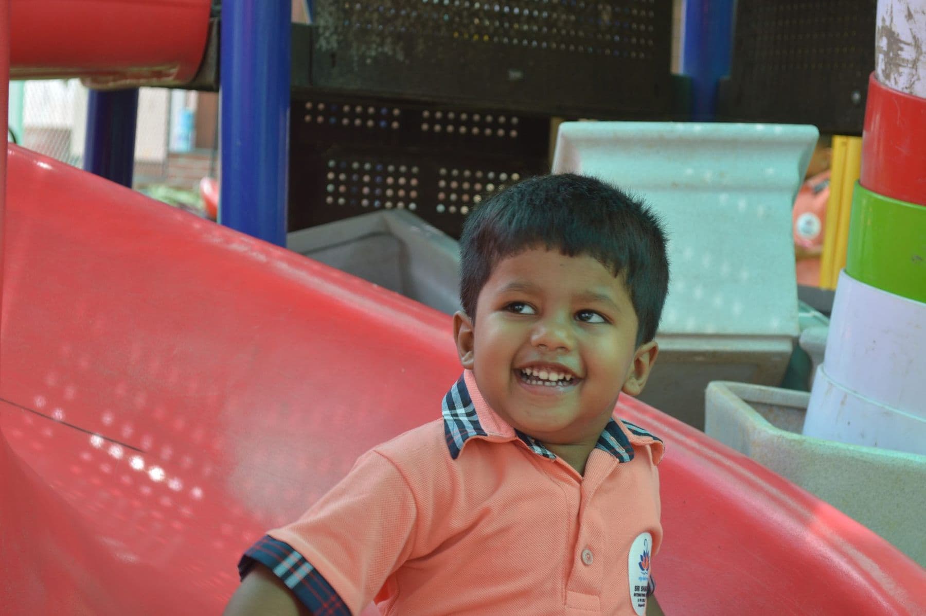 A boy laughing as he whooshes down the red slide