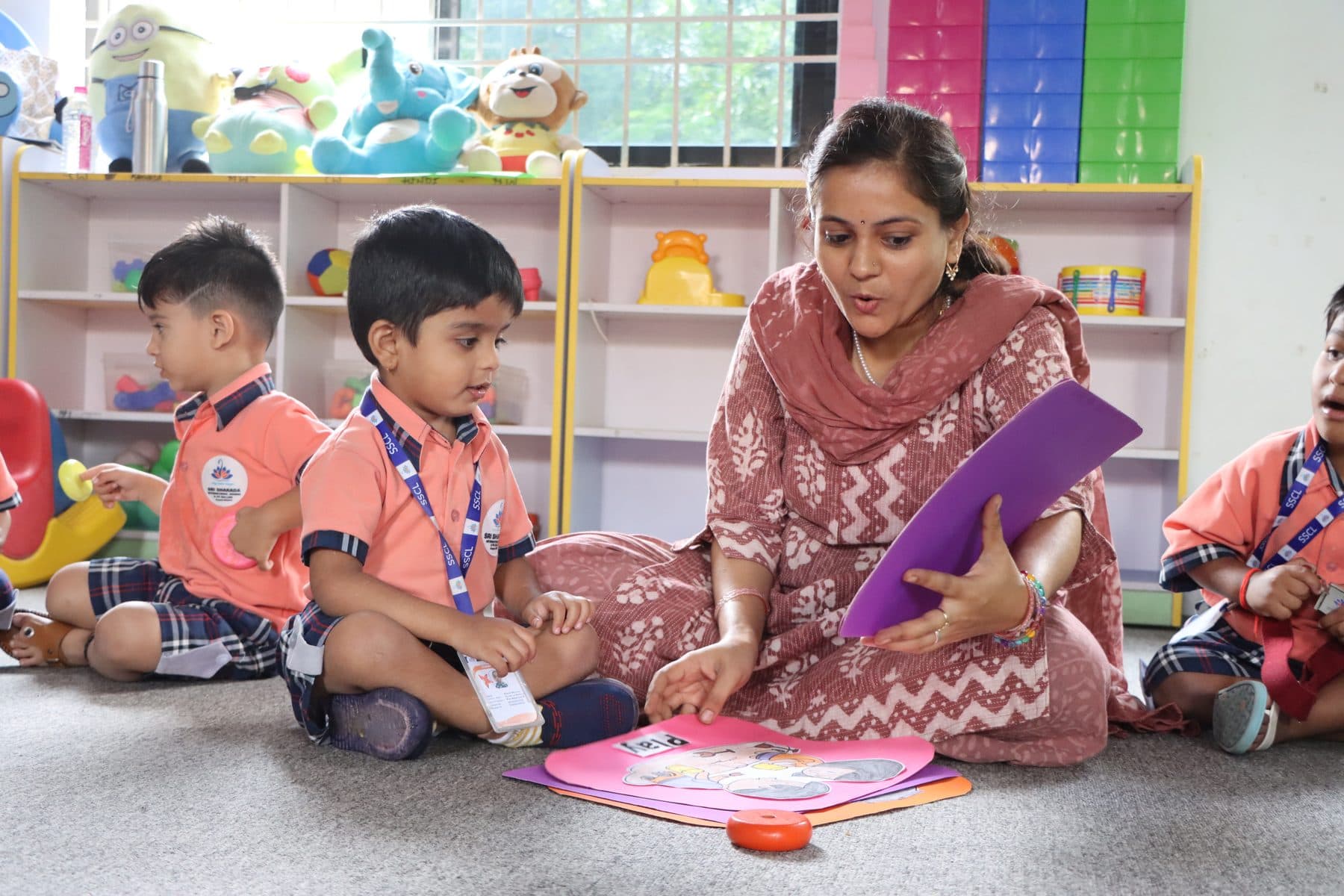 A teacher sitting on the floor reading with her little ones