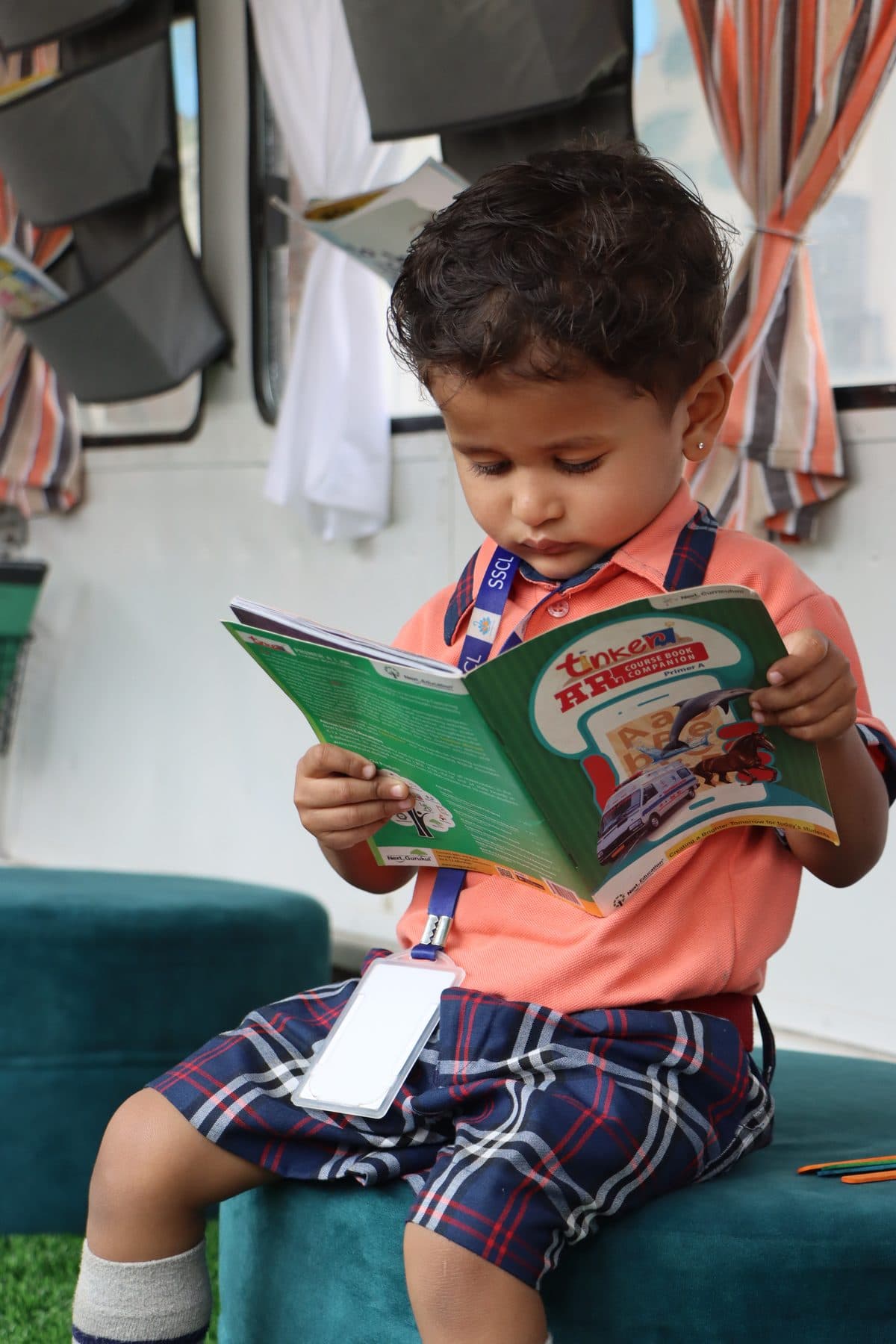 A toddler reading a green picture book in the library bus