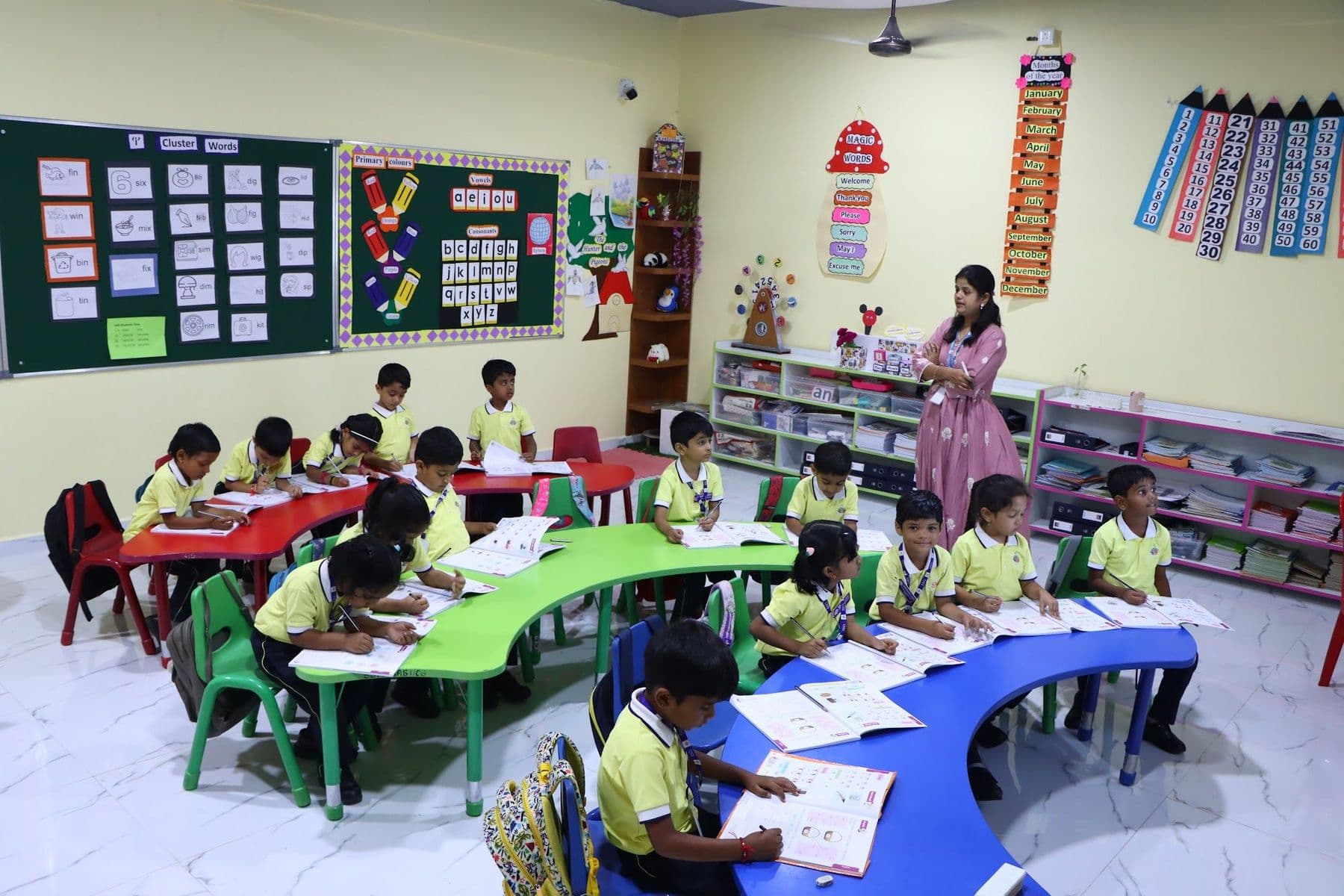 A full classroom of children working at curved tables with their teacher